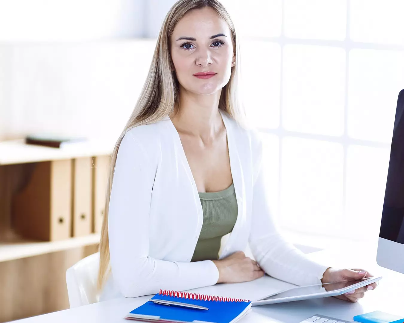 en kvinna  sitter på kontor utbildad ekonom klädd i ljus kofta akavia aspekt